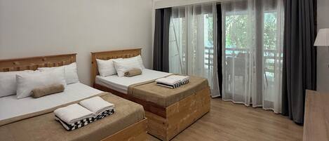 A modern hotel room with two wooden beds, a large skylight, and a view of greenery outside.