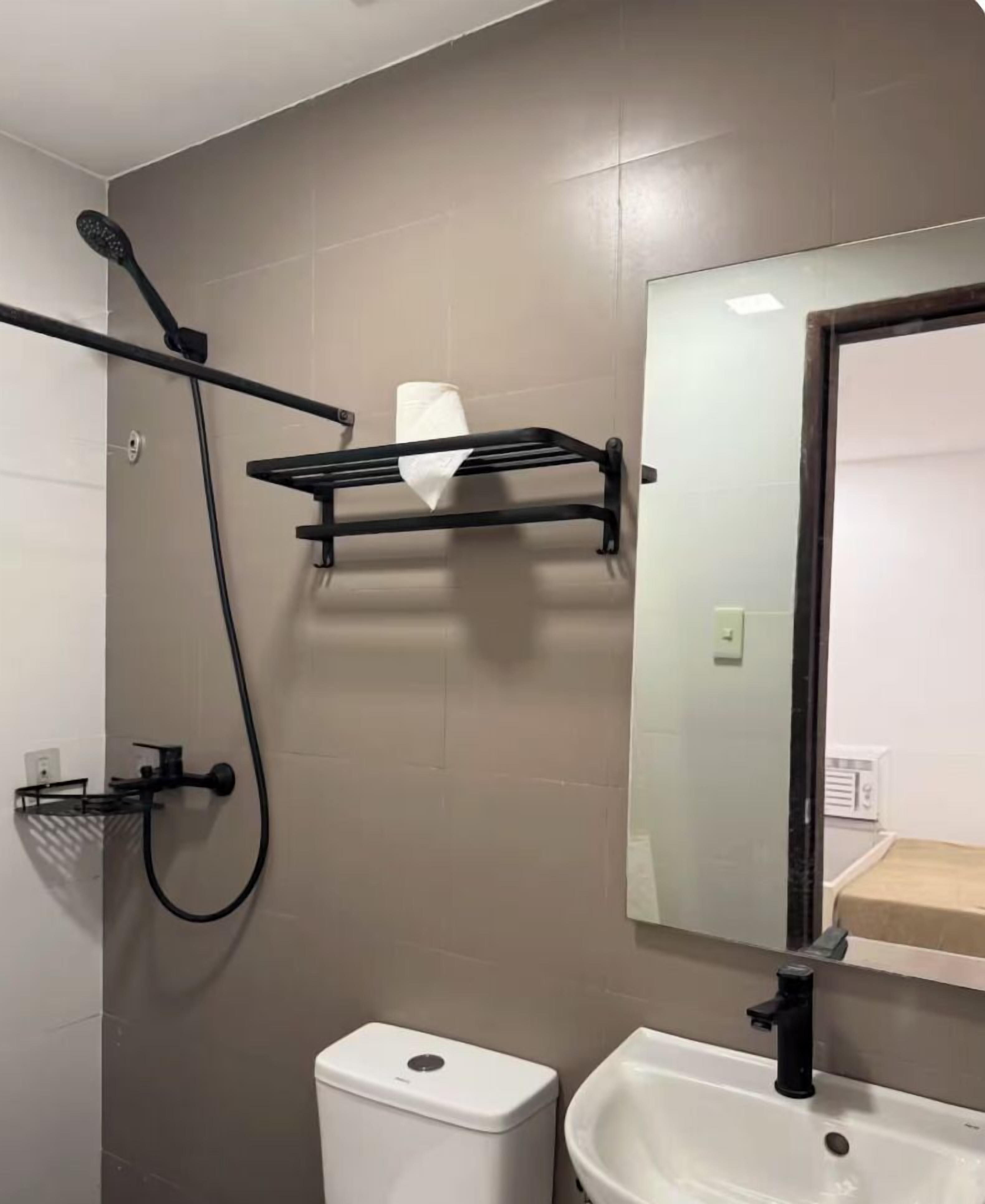 A bathroom with a shower, toilet, sink, and a mirror.