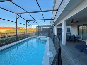 A covered outdoor swimming pool with a patio area, a hot tub, and a view of the surrounding landscape. - The Dream Getaway Retreat Near Disney (Davenport)