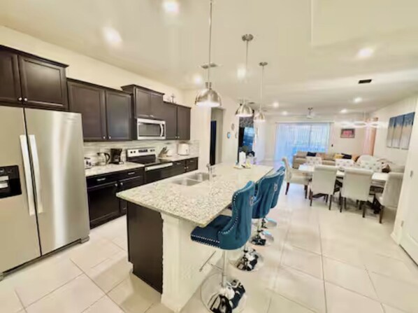 A modern kitchen with dark cabinets, stainless steel appliances, and a central island with bar stools.