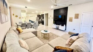 Een moderne woonkamer met een hoekbank, een eethoek en een keuken.