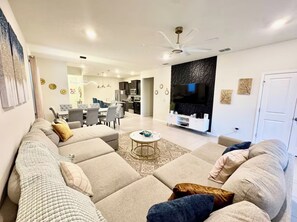 A modern living room with a sectional sofa, a dining area, and a kitchen. - The Dream Getaway Retreat Near Disney (Davenport)