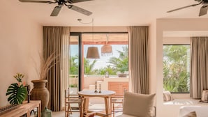 A modern living room with a sofa, a dining table, and a ceiling fan. - Best-Located Beach Suite with pool. (Tulum)
