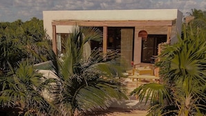 A modern house with a flat roof, large glass windows, and a wooden deck. - Best-Located Beach Suite with pool. (Tulum)