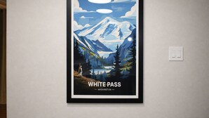 Un quadro con un poster di un paesaggio montano con su scritto 'WHITE PASS - WASHINGTON'.