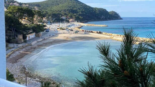 A coastal town with a beach, boats, and a mountainous backdrop. - Renovated 4 Pers Studio with Garden and Private Parking (83270 ST CYR)