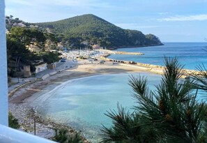 Une ville côtière dotée d’une plage, de bateaux et bordée de montagnes.