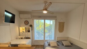 A bedroom with a bed, bedside table, and a TV mounted on the wall. - Renovated 4 Pers Studio with Garden and Private Parking (83270 ST CYR)
