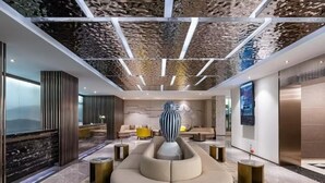 A modern lobby with a central seating area, a decorative sculpture, and a large TV screen. - Crystal Hotel Hangzhou West Lake Wulin (Hangzhou)