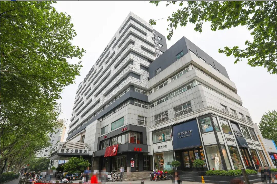 Un edificio de varios pisos con locales comerciales en la planta baja, que incluyen un restaurante y una tienda con letreros visibles.