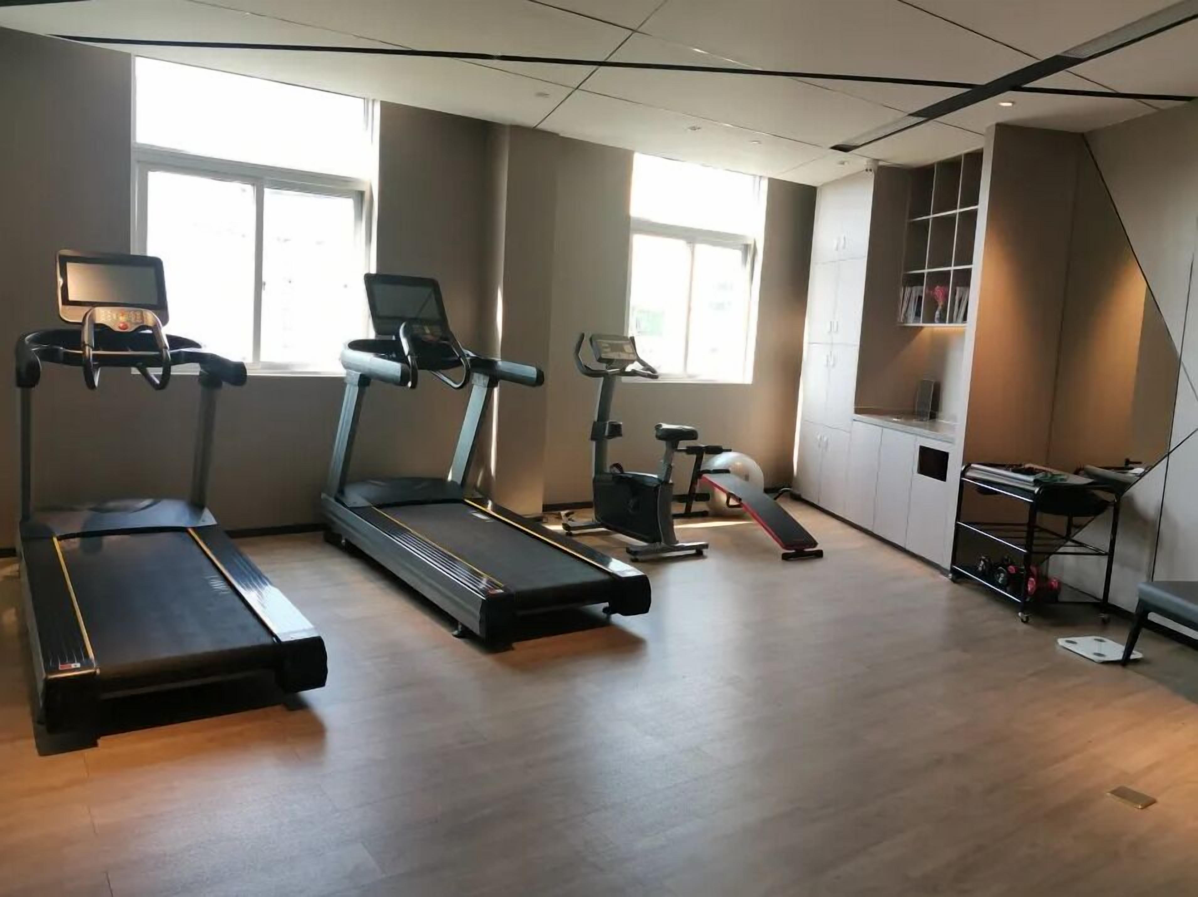 Ein Fitnessraum mit Laufbändern, Fahrrädern und einer Gewichtshalterung.