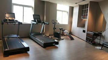 Ein Fitnessraum mit Laufbändern, Fahrrädern und einer Gewichtshalterung.