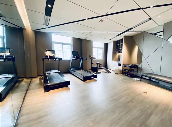A modern gym with treadmills, elliptical machines, and a bench.