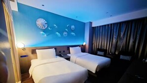 A hotel room with two beds, a blue accent wall, and a curtain-covered window. - Crystal Hotel Hangzhou West Lake Wulin (Hangzhou)