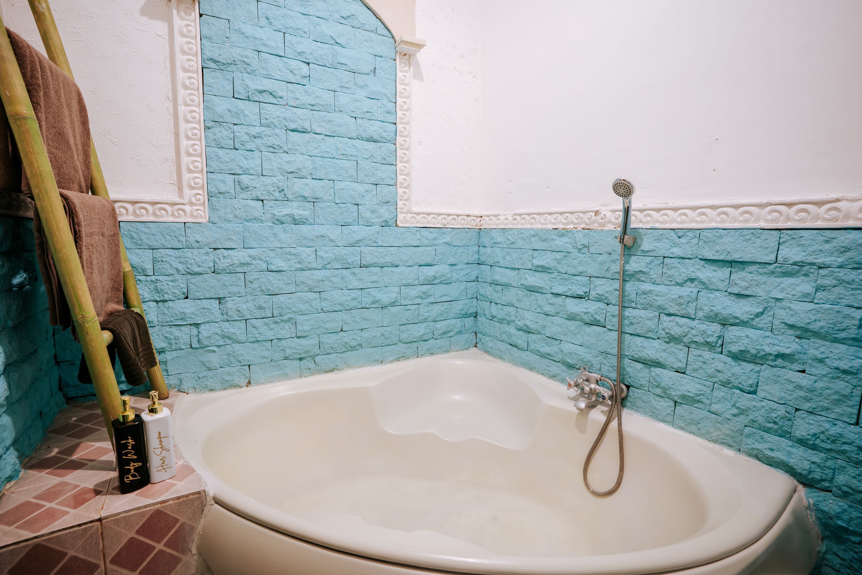 A bathroom with a bathtub, a shower, and a towel rack with towels.