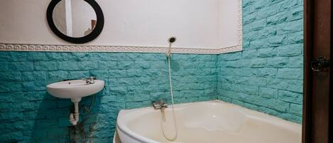 A bathroom with a white bathtub, a sink, and a mirror on the wall.