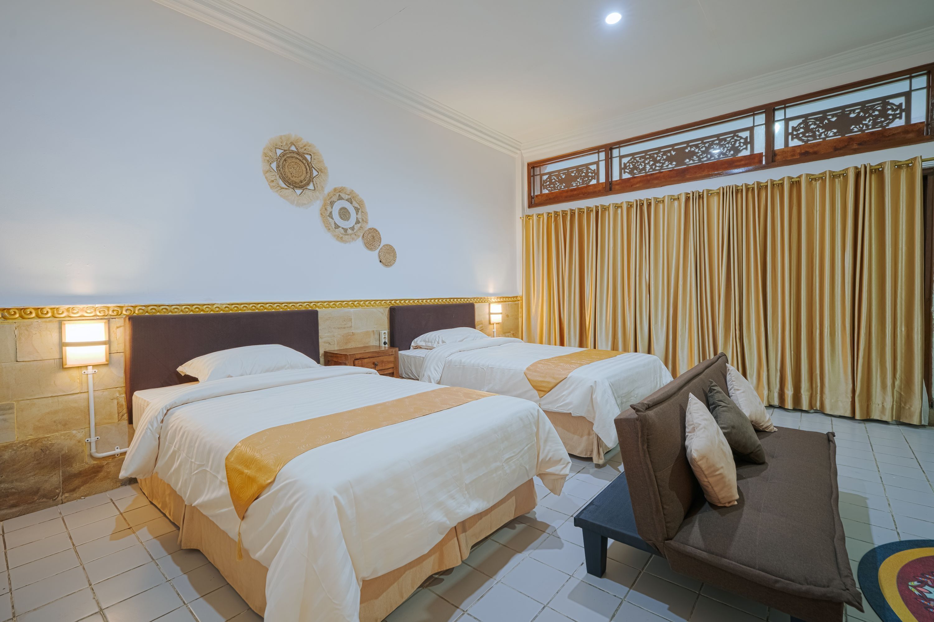 Een hotelkamer met twee bedden, een bank, een decoratieve wand en gordijnen.