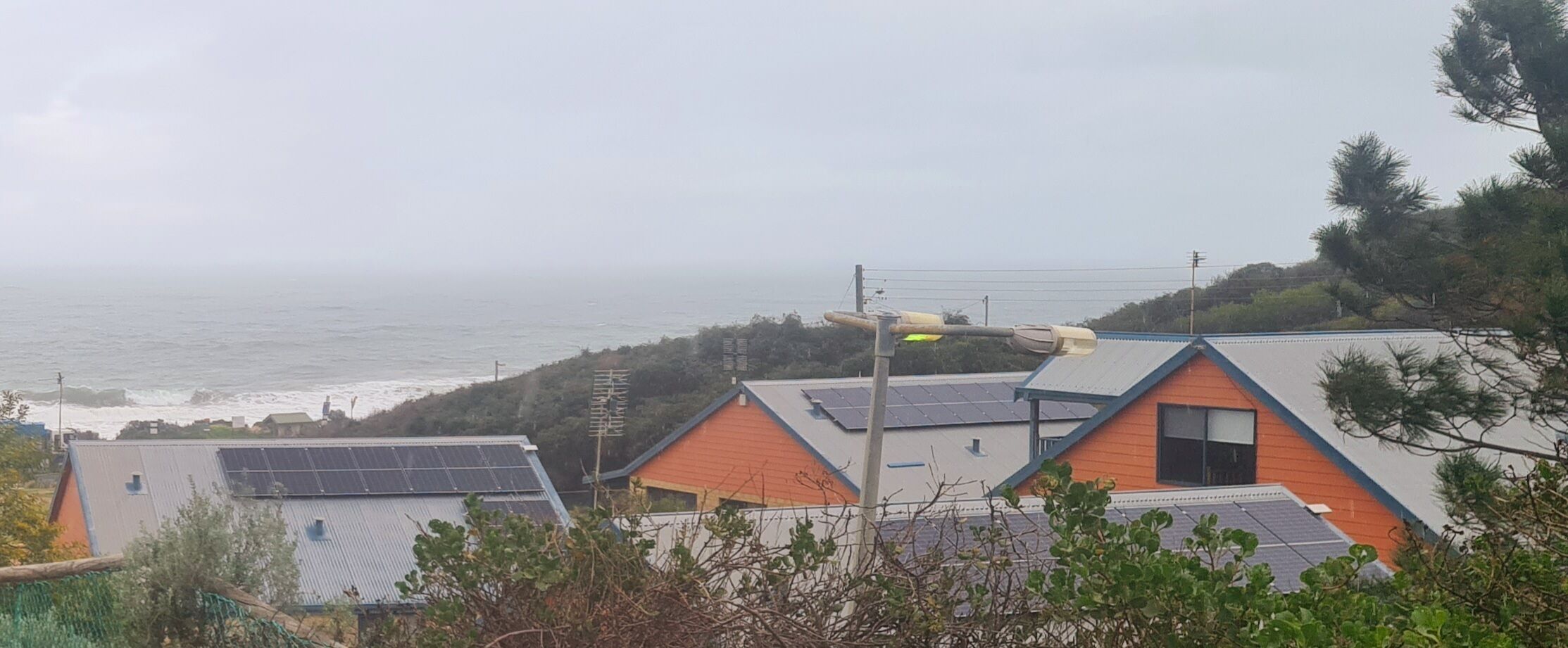 A coastal residential area with houses featuring solar panels and a streetlight.