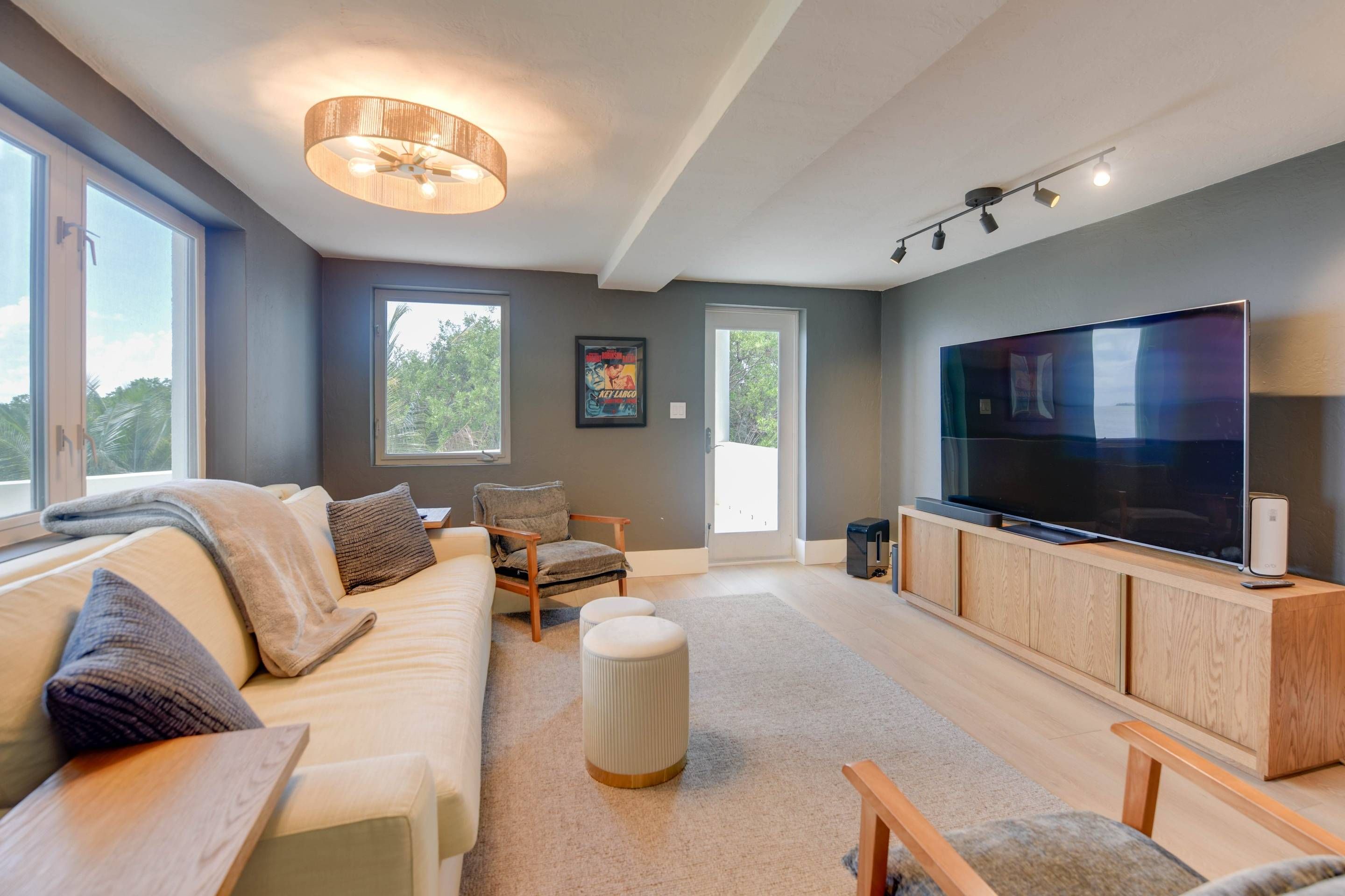 A modern living room with a large flat-screen TV, a sofa, a chair, and a wooden entertainment unit.