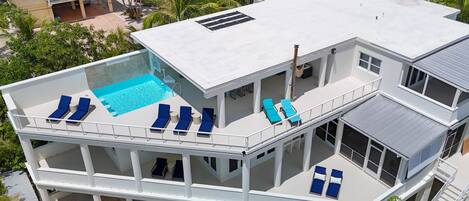 Ein mehrstöckiges Gebäude mit Pool auf dem Dach, Balkonen inklusive Liegestühle und einem überdachten Außenbereich.