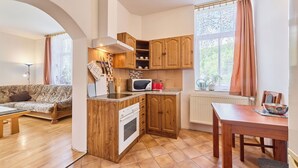 A compact kitchen with wooden cabinets, a microwave, and a stove. There is a dining table with a bowl on it.
