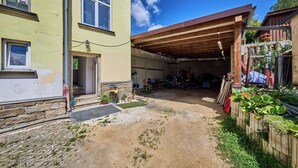 A residential property with a covered garage, a stone wall, and a garden area with potted plants.
