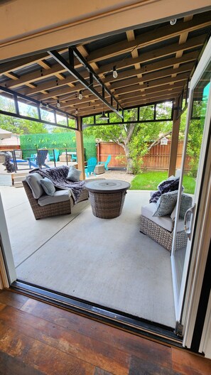 An outdoor patio with wicker furniture, a round table, and a pergola structure. - Downtown Home-Heated Plunge Pool Outdoor Oasis (Loveland)