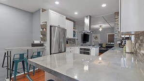 A modern kitchen with white cabinets, stainless steel appliances, and a large island with bar stools.