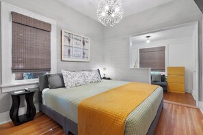 A bedroom with a bed, bedside table, lamp, dresser, and a window with blinds. - Downtown-Heated Plunge Pool King Bed (Loveland)