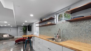 A modern kitchen with a wooden countertop, white cabinets, and a tiled backsplash.