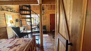 A wooden interior with a dining table, chairs, a staircase, and a red door. - Cowboy Cabin -tucked into the woods near Hatcher Pass Recreation Area. (Palmer)