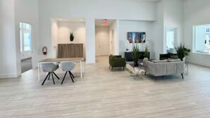 A spacious, modern living area with a dining table and chairs, a sofa, and a TV.