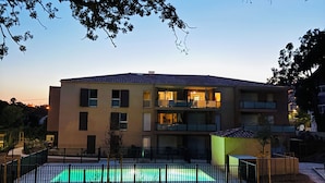 A modern multi-story building with a swimming pool, surrounded by greenery and a fence. - T2 apartment plus cabin with terrace and pool (Bormes-les-Mimosas)