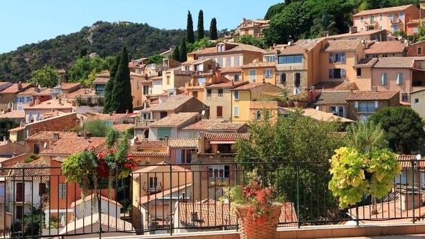 A hillside town with terracotta-roofed buildings, a prominent cypress tree, and a balcony with hanging flowers. - T2 apartment plus cabin with terrace and pool (Bormes-les-Mimosas)