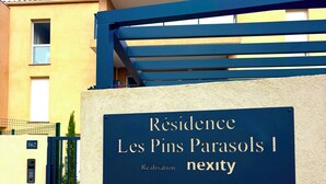 A sign for Residence Les Pins Parasols 1 nexty, with a modern architectural design and a clear sky in the background. - T2 apartment plus cabin with terrace and pool (Bormes-les-Mimosas)
