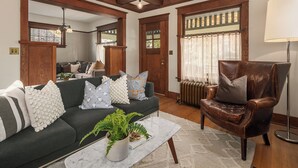 A living room with a dark green sofa, a leather armchair, and a marble coffee table with a potted plant. - Refined Wallingford Craftsman • Perfect Family Retreat near Parks, Zoo & UW (Seattle)