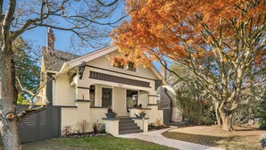 A two-story house with a front porch, a chimney, and a well-maintained lawn. - Refined Wallingford Craftsman • Perfect Family Retreat near Parks, Zoo & UW (Seattle)