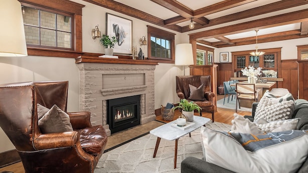 A cozy living room with a fireplace, leather armchairs, a grey sofa, and a dining area with wooden furniture. - Refined Wallingford Craftsman • Perfect Family Retreat near Parks, Zoo & UW (Seattle)