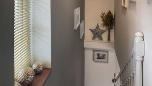A staircase with a white railing, a wooden shelf with decorative glass spheres, and wall-mounted star decorations.