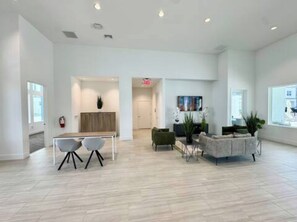 A spacious, modern lobby with a light-colored floor, a reception desk, and seating areas with chairs and a sofa. - The Fantasy Retreat4 by Disney/Universal/seaworld (Davenport)