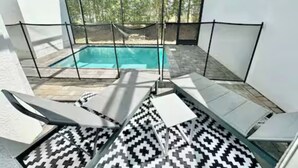 Área da piscina com vista clara, cercada por paredes brancas e piso estampado.