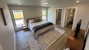 A bedroom with a bed, a TV, a rug, and a window.