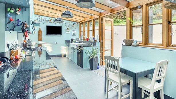 A kitchen with a large island, wooden beams, and a TV mounted on the wall. - 4 bedroom accommodation in Frogham, Fordingbridge (Frogham, Fordingbridge)