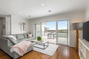 A modern living room with a grey sofa, a coffee table, and a TV on a stand.