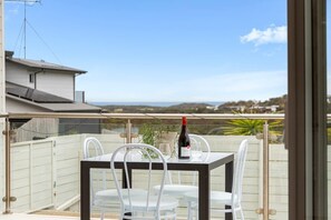 Ein Balkon mit Tisch und Stühlen, einer Weinflasche und Blick auf die Landschaft.