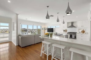 A modern kitchen with a large island, white cabinetry, and pendant lighting.