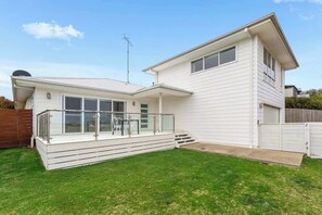 Ein zweistöckiges Haus mit überdachter Terrasse und umzäunter Garten.
