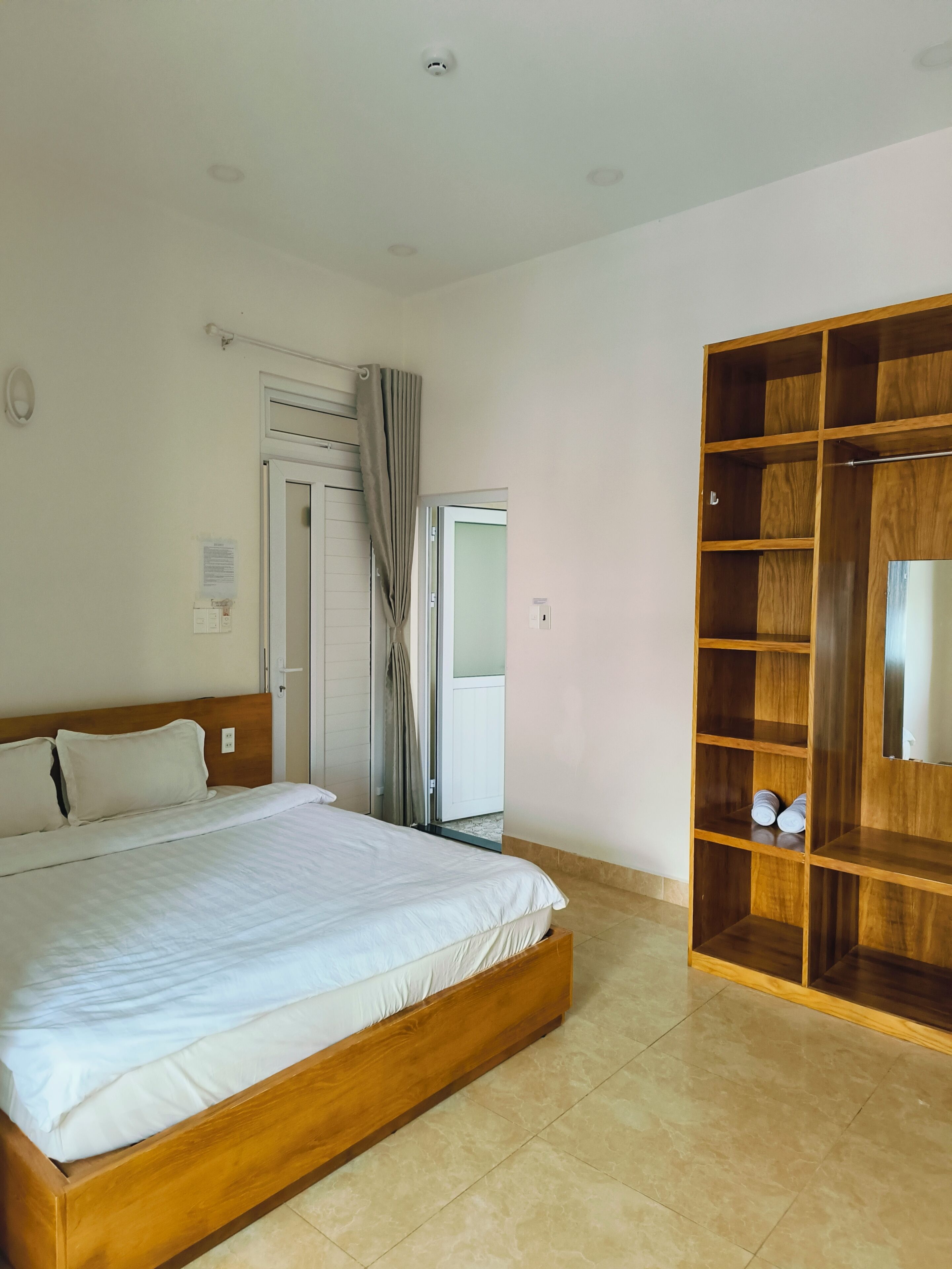 Quarto com cama de madeira, guarda-roupa e porta que dá para outro cômodo.