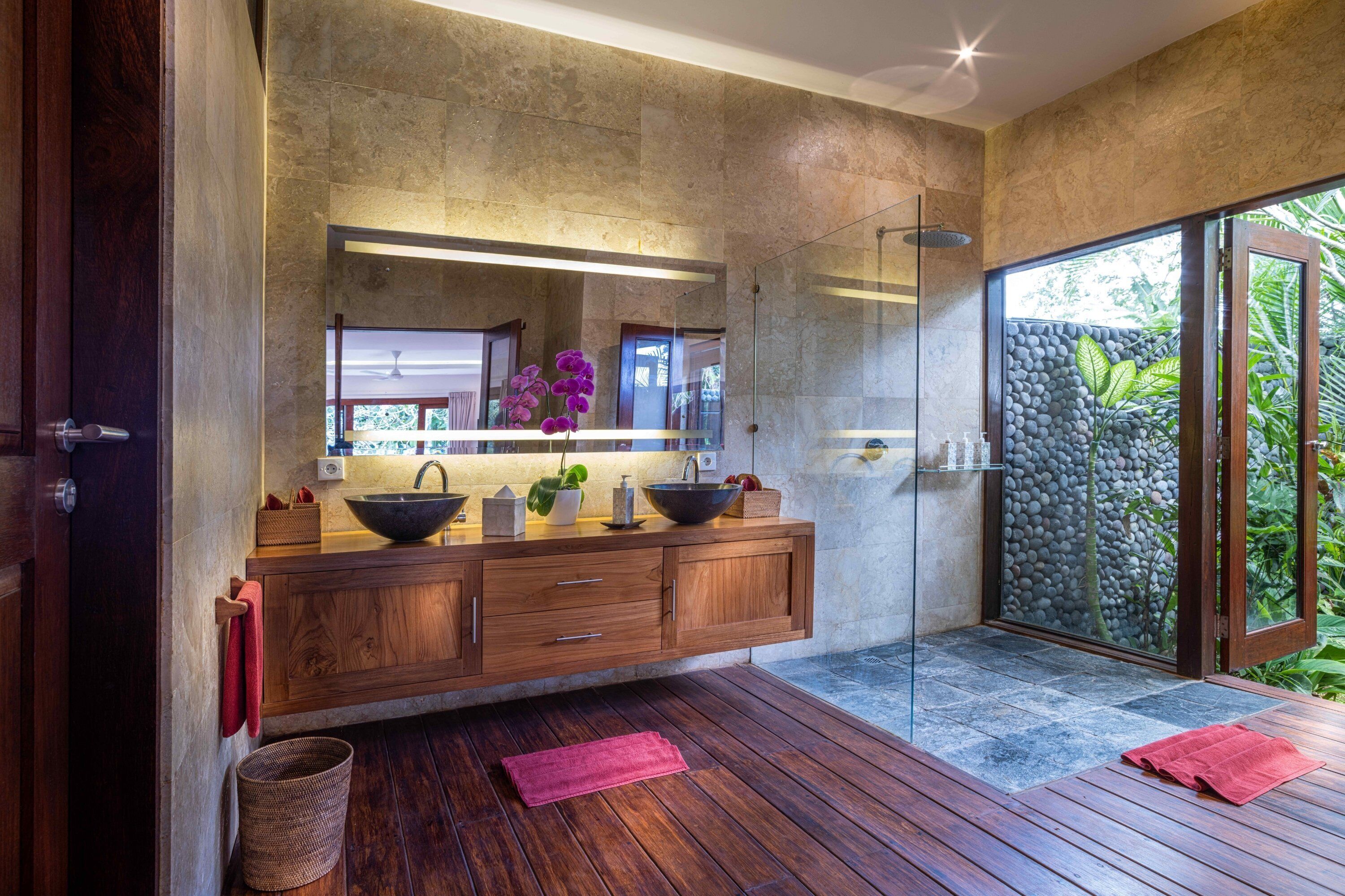 A modern bathroom with a wooden vanity, a large mirror, and a glass shower enclosure.