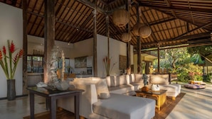 A spacious living area with a high ceiling, a sofa set, a dining table, and decorative items. - Villa Crystal Castle (Ubud)